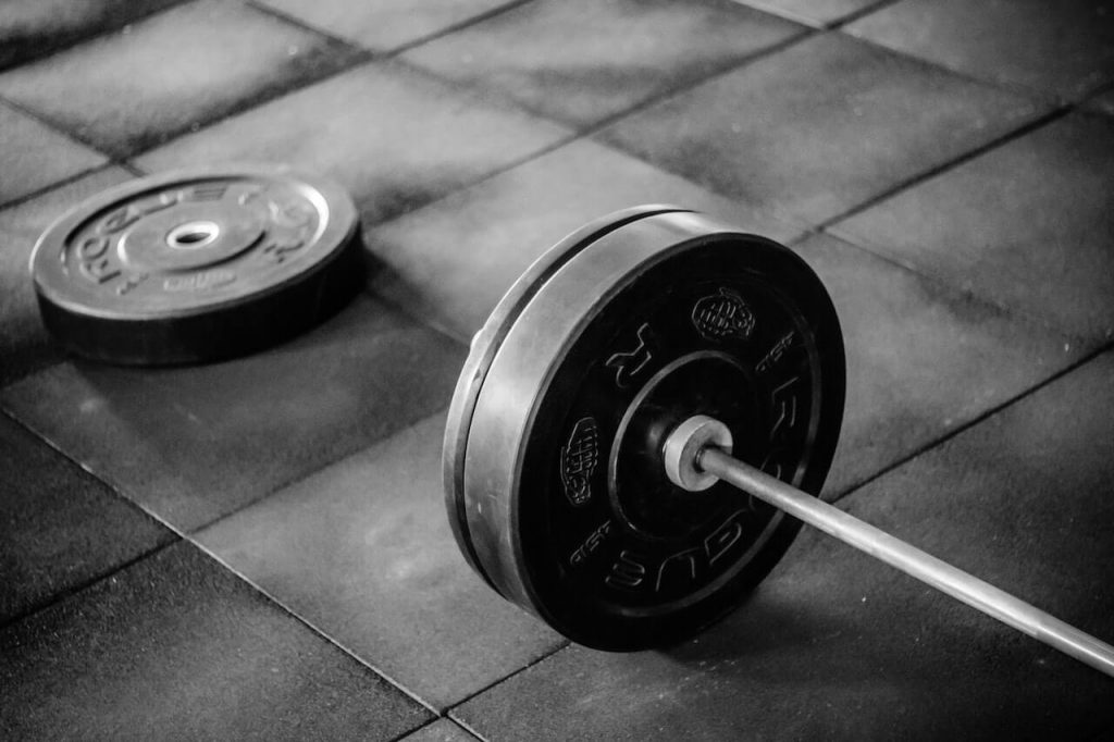 An image displaying a barbell and weight plates, essential equipment for strength training and weightlifting exercises.